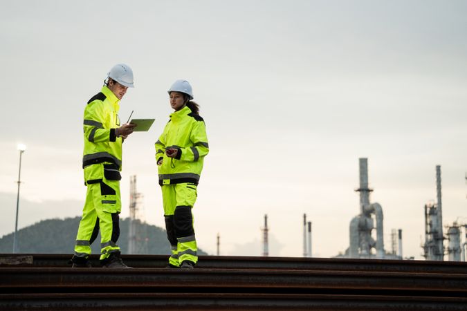 Engineer worker watching work monitor on digital tablet at refinery factory at night