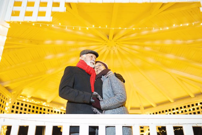 Mature man and woman holding each other under a bright gazebo