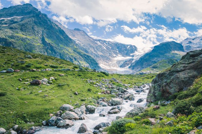 Shallow river flowing along rocky shore in bright day
