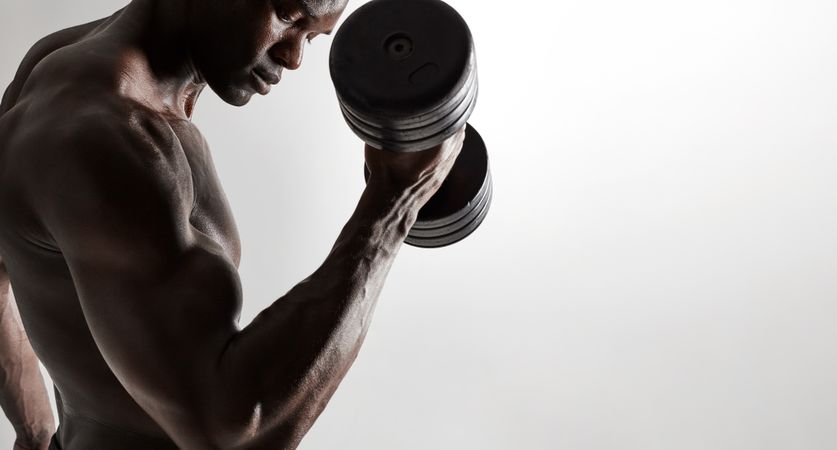 Muscular male model lifting heavy dumbbells