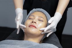 Young woman doing facial massage in beauty clinic.