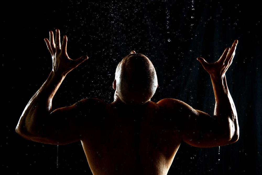 Anonymous muscular male under rain