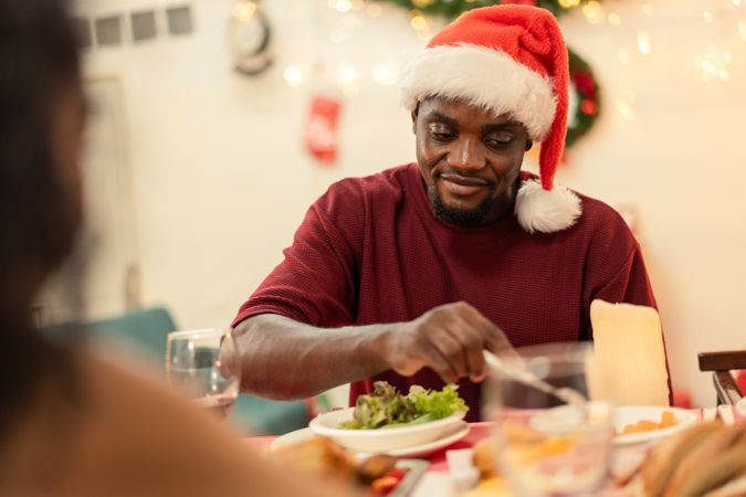 Smiling Black man wearing a Santa hat enjoying a Christmas holiday