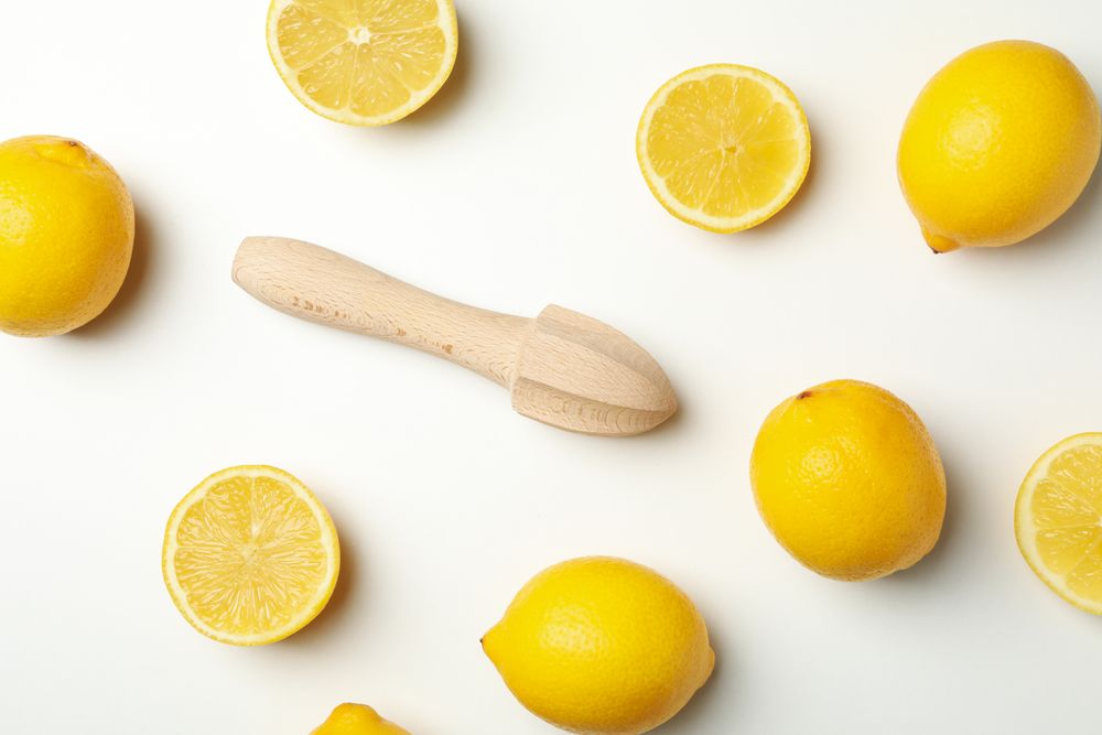 Lemons and wooden juicer on light background, top view. Ripe fruit