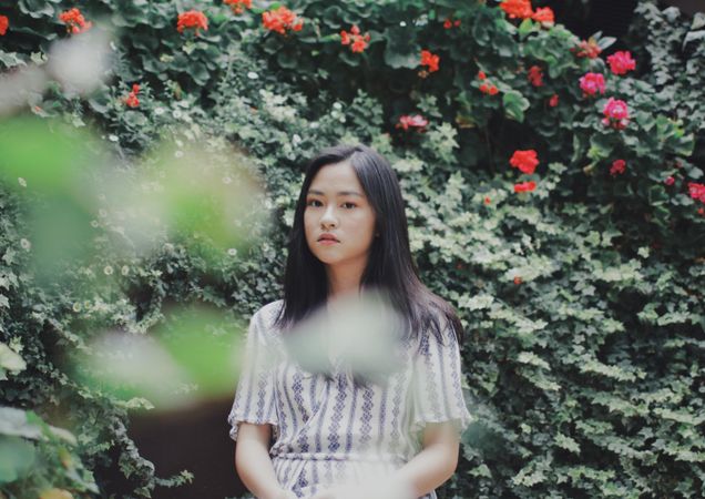 Woman in striped top posing near bushes and flowers