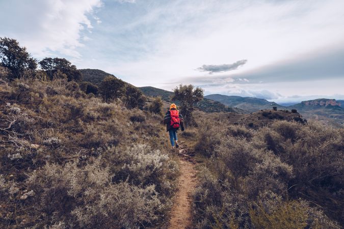 Hiker with backpack walking along pathway in autumn forest