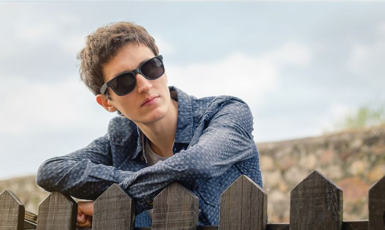 Hipster man with sunglasses over a fence