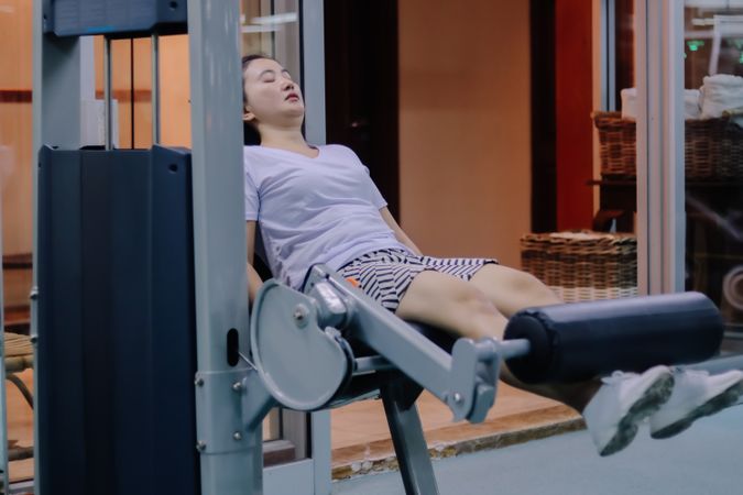 A woman uses a leg extension machine at an indoor gym.