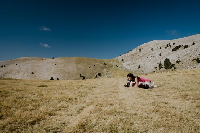 Woman playing with big dog on hill meadow