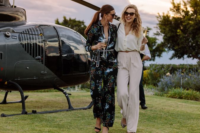 Women friends walking away from helicopter with wine