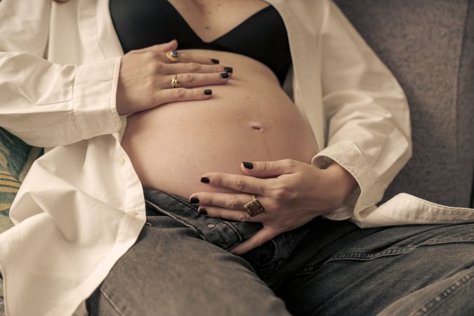 Close-up detail of a pregnant woman holding her bare belly.