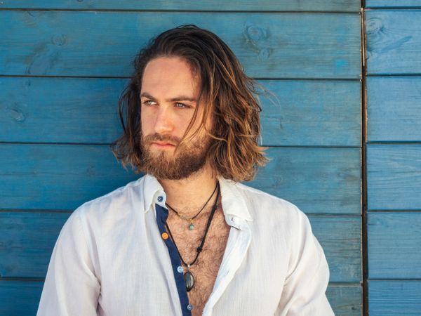 Cheerful guy sitting near blue wall