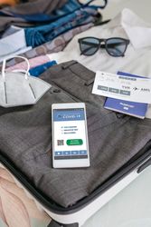 Businessman suitcase prepared for business trip with covid passport on mobile