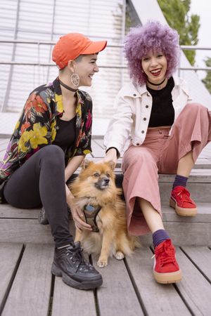 Women in colorful shirt and with pink hair training dog and having fun