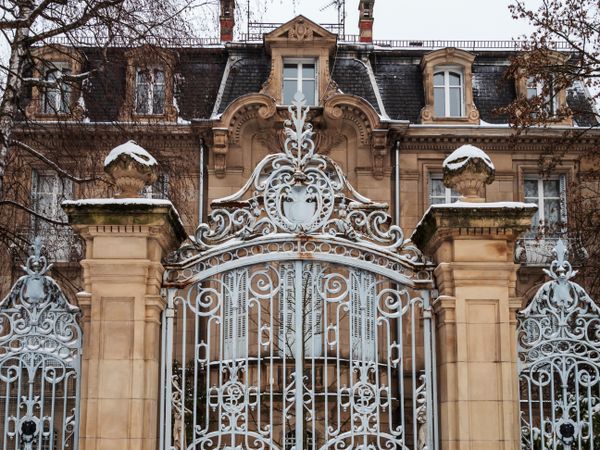 An old manor with beautiful gates is covered with snow.