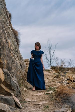 Woman in long blue dress walking in natural landscape