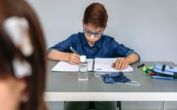 Face mask and hand sanitizer on a student's desk