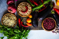 Top view of fresh vegetables and grains on cutting board with copy space