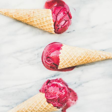 Three cones of dark berry ice cream on marble slab, square crop