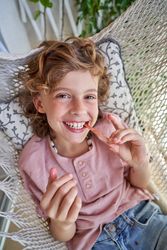 Cheerful boy finishing eating ice cream in hammock