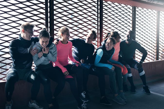 Smiling group of sporty people sitting by window and having fun