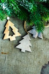 Green wintry branch with tree shaped wooden ornaments