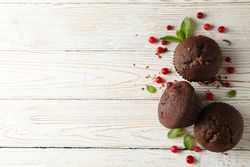 Composition with chocolate muffins and berries on wooden background