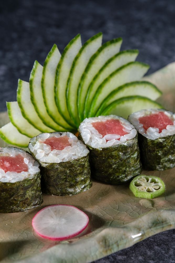 Delicious tuna sushi rolls served with fresh cucumber slices arranged on marble plate
