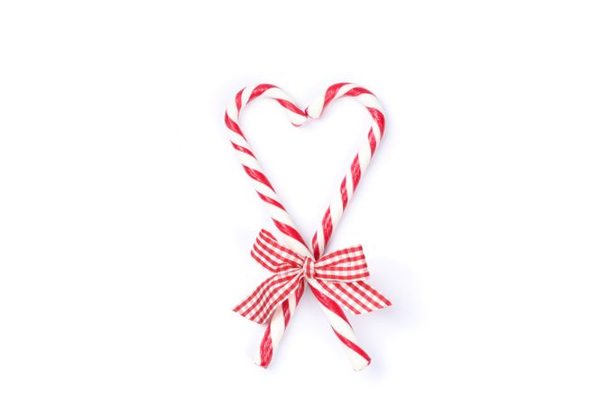 Sweet candy canes with bow isolated on plain background