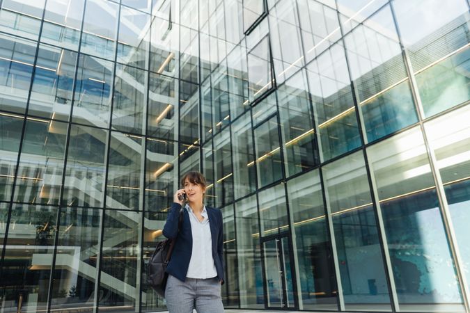 Smiling entrepreneur browsing smartphone outside office building