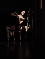 Ballerina sitting in plie on chair in dark room