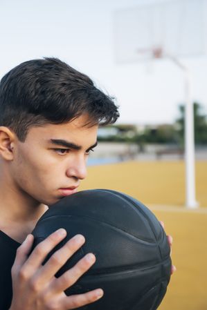 Young man playing on yellow basketball court outdoor.