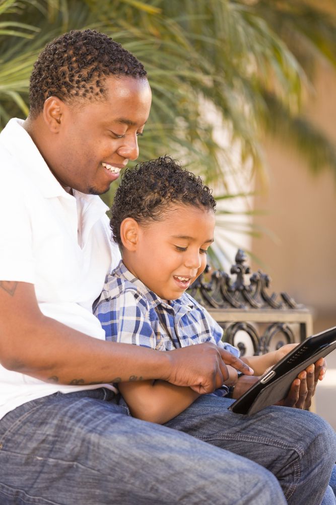 Black Father and Son Using Digital Tablet