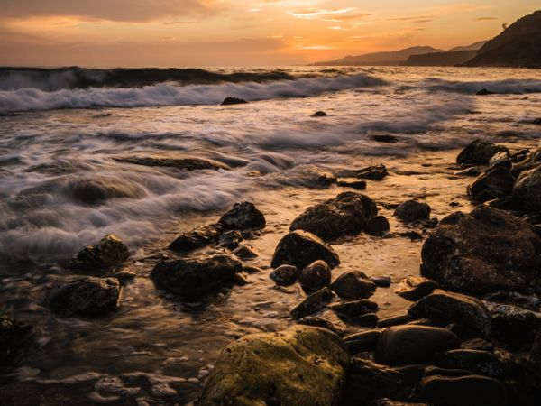 Stony seashore and waves at beautiful sunset