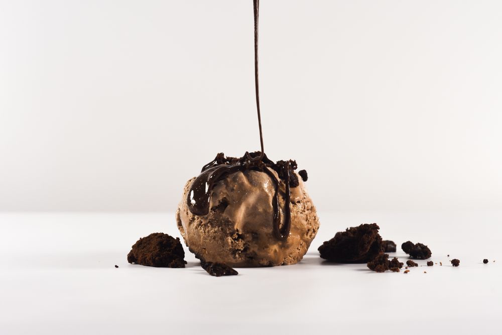 Scoop of chocolate brownie ice cream with syrup pouring