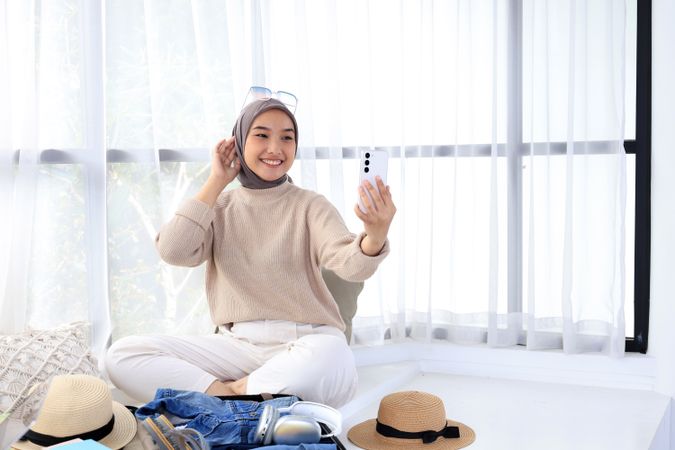 Young Asian Muslim Woman Taking Selfie in Hotel While Traveling