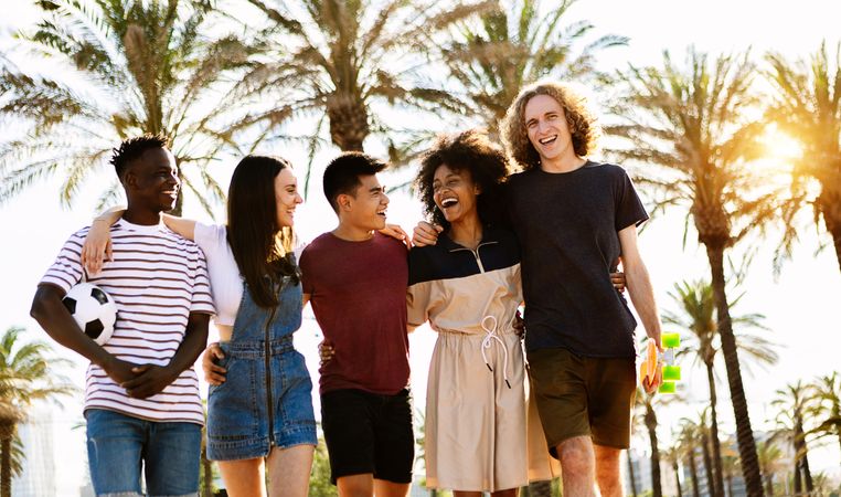 Smiling multi-ethnic friends strolling outside at dusk