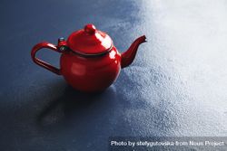 Shiny red tea pot on blue table 5zlqQb