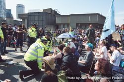 London, England, United Kingdom - April 19th, 2019: Police kneeling speaking to sitting protesters 0JGJ85