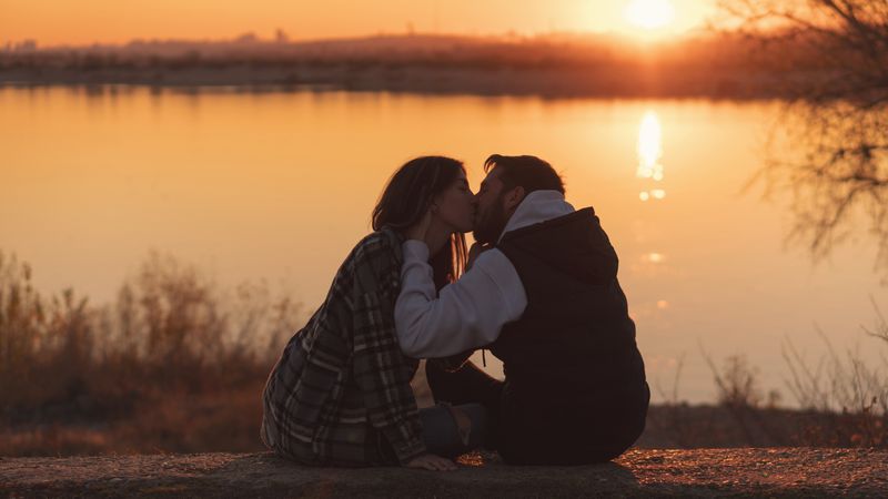Couple sitting sunset lake