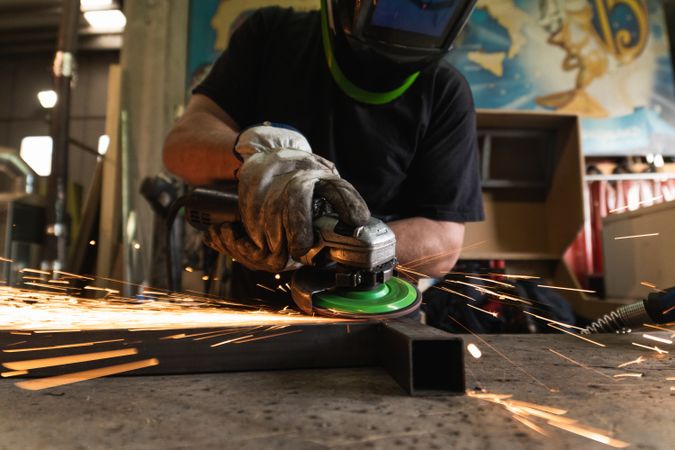 Male worker using electric grinder in workshop