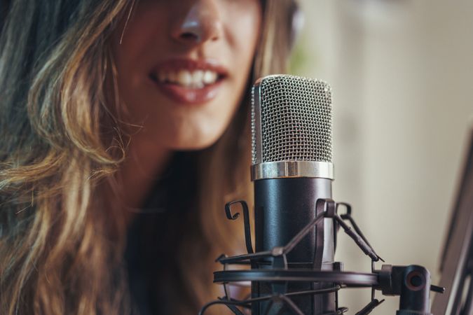 Podcast host recording voice in studio with professional microphone