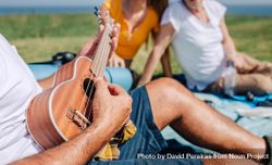 Close up of man playing ukulele on family picnic 4ZWG9b