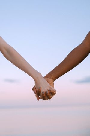 Cropped image of Black hand and white hand holding each other