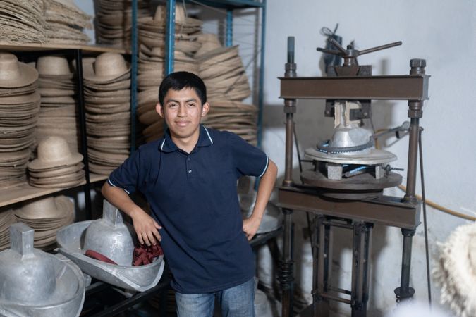 Portrait of a young Hispanic worker in a hat workshop
