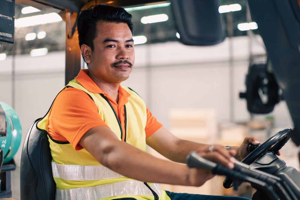 Man in high visibility vest driving forklift in distribution center