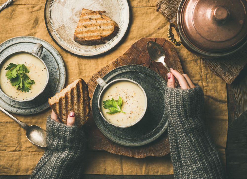 Woman with toast, spoon, and celery soup in cup