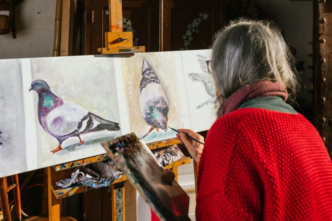 Anonymous woman painting on canvas in garden