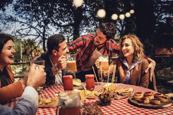 Group of close-knit family friends drinking and eating together having fun in the countryside