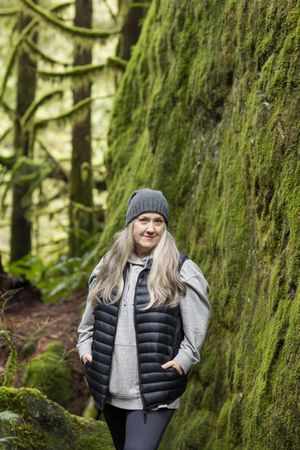 Content woman posed next to a mossy rock wall